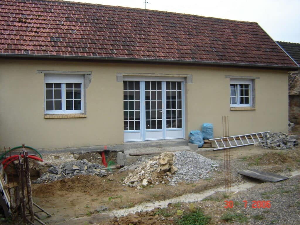 Façade d'une maison en cours de finition, matériaux au premier plan