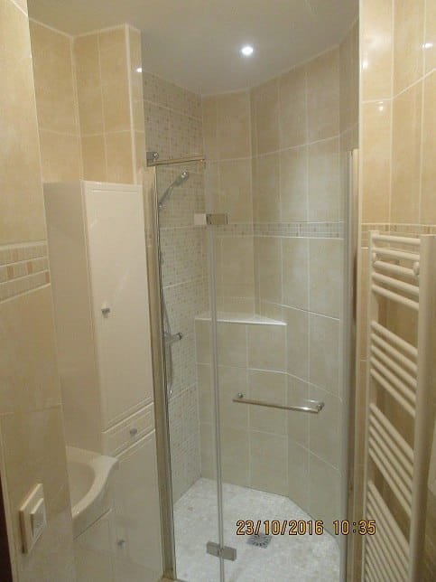 Salle de bain beige avec douche d'angle vitrée