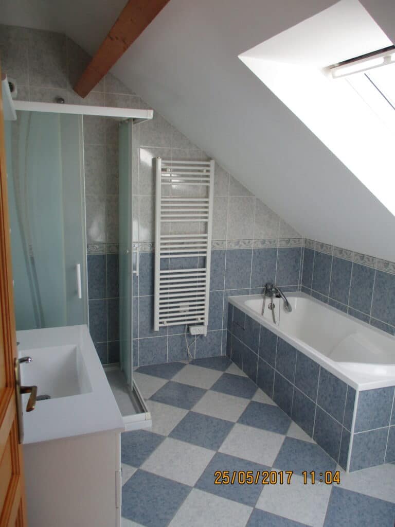 Salle de bain mansardée avec baignoire d'angle et douche